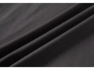 Primo piano di un tessuto in cotone grigio scuro con trama morbida e pieghe naturali.