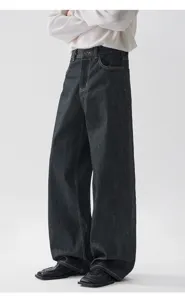 Dettaglio dei jeans scuri a zampa in stile vintage con un taglio ampio e confortevole.