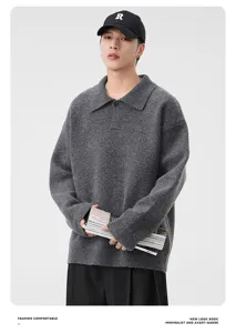 Close-up of model wearing grey lapel knit sweater with magazines in minimalist studio
