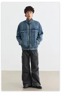 Gros plan sur les détails de la veste en denim lavé vintage avec col montant et poches.