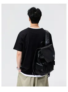 Casual mens short sleeve t-shirt and leather backpack detail shot in studio lighting.