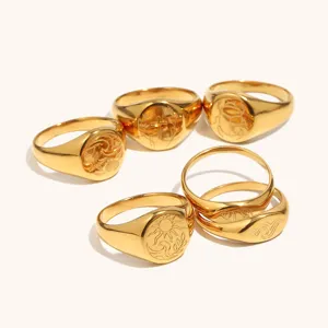 Primer plano de anillos de acero inoxidable dorado con intrincados grabados de olas y sol.