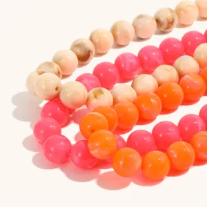 Primo piano sui dettagli della collana di perline colorate, rosa, arancioni e marmorizzate.