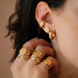 Primer plano detallado de anillos y pendientes de acero inoxidable con baño de oro.