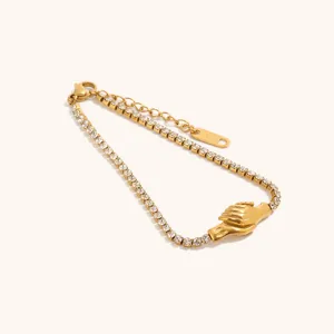 Primo piano dei dettagli del bracciale con strass placcato oro, che mostra il ciondolo mani e pietre.