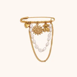 Broche en acier titane doré avec chaînes de perles, pendentifs soleil, ours et cœur.