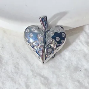 Close-up view of silver heart pendant with sparkling zircons and heartbeat line detail.