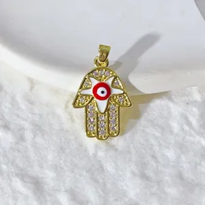 Primo piano di un ciondolo a mano di Fatima dorato con motivo malocchio e zirconi lucenti.
