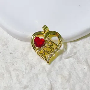 Gold heart MOM pendant close-up, featuring red gemstone and sparkling pave zircon details.