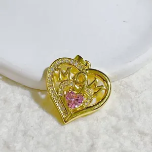 Close-up detail of the gold heart pendant with MOM lettering and sparkling pink crystal stone.