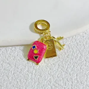 Gold-plated travel charm pendant with pink suitcase and airplane for DIY bracelets.