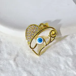 Splendido ciondolo cuore occhio malvagio dorato in primo piano, zircone brillante.