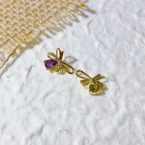 Primo piano dettaglio di ciondoli gioielli fai da te in rame dorato 18k con zirconi fiocco.