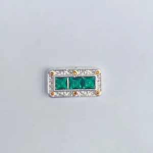 Primo piano del ciondolo rettangolare per bracciale DIY con pietre verdi e gialle, metallo.