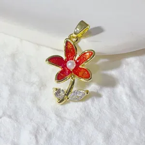 Detail shot of copper red enamel flower pendant with sparkly zircon leaves and pearl center.