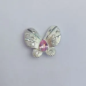 Nahaufnahme eines Schmetterling-Schmuckanhängers mit rosa Edelstein und klaren Kristallen.