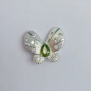 Nahaufnahme eines Schmetterling-Schmuckanhängers mit grünem Stein und hellem Zirkonia.