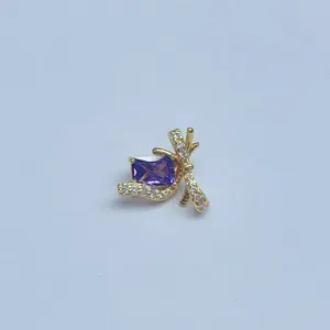 Nahaufnahme eines vergoldeten Schmetterlingsanhängers mit lila Edelstein für DIY Schmuck.