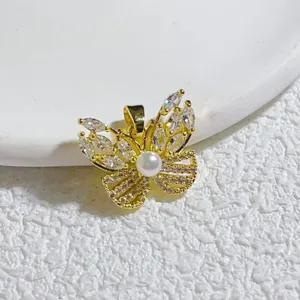 Nahaufnahme eines goldenen Schmetterlingsanhängers mit funkelnden Zirkonia und einer weißen Perle.