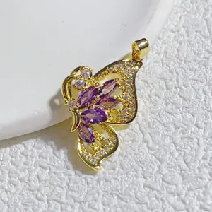 Nahaufnahme Detail eines vergoldeten Schmetterling-Anhängers mit lila und weißen Zirkoniasteinen.