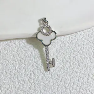 Close-up of a gold-plated key pendant featuring mother-of-pearl clover and zircons.