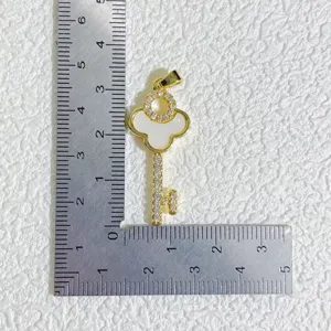 Detail view of gold-plated key pendant with mother-of-pearl and zirconia size reference.