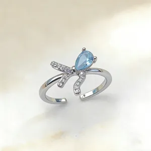 Eleganter offener Ring mit funkelndem tropfenförmigen blauen Stein und feinen Zirkonia-Schleifen.