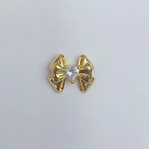 Nahaufnahme eines vergoldeten Schleifen DIY Charm Details mit Kristallherz in der Mitte.