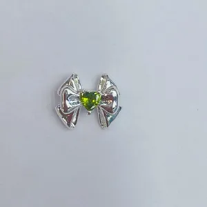 Detailansicht eines silbernen Schleifen-Charms mit grünem Herz-Edelstein für DIY-Schmuck.