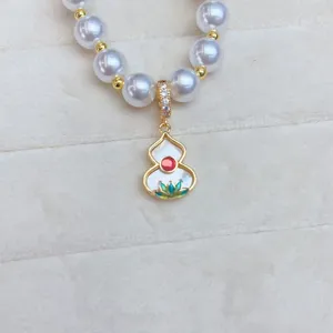 Gros plan détaillé du pendentif gourde en cuivre plaqué or avec nacre et perles brillantes.