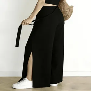 Detail view of black high-waisted wide-leg trousers with stylish side slit and tie belt.