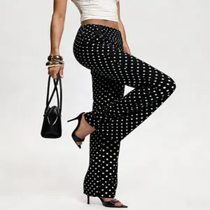 Close-up detail view of black polka dot flare pants, showcasing retro style and slim fit.