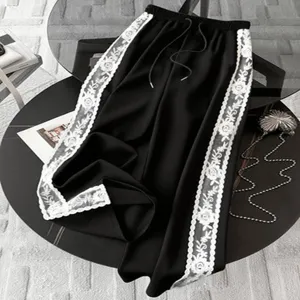 Detail of black wide-leg pants featuring white lace side stripes and comfortable drawstring waist.