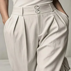 Close-up detail of high-waisted pleated trousers, drapey fabric and double button closure.