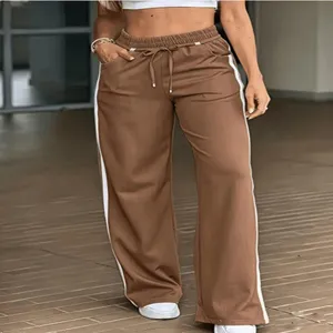 Vista di dettaglio dei pantaloni larghi casual marroni da donna con strisce laterali bianche.