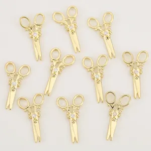 Detail view of gold scissor pendants with cubic zirconia, ideal for DIY jewelry making.