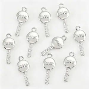 Close-up view of silver key pendants with love engraving and clear rhinestones for DIY jewelry.
