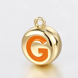 Nahaufnahme Detailansicht runder goldener Metall Anhänger mit leuchtend orangefarbenem Buchstabe G.