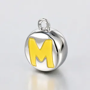 Silberfarbener runder Metallanhänger mit leuchtend gelbem Emaille Buchstaben M Detail Makro.