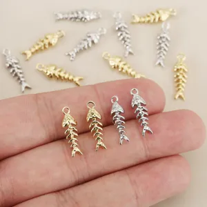 Detailed view of cute fish bone pendants in gold and silver, perfect for DIY jewelry making.
