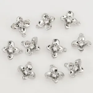 Close-up detail of silver four-petal flower DIY charms featuring sparkling central cubic zirconia stones.
