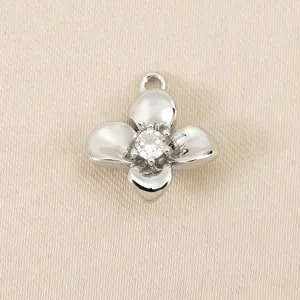 Close-up detail of a metal four-petal flower pendant with central cubic zirconia charm.
