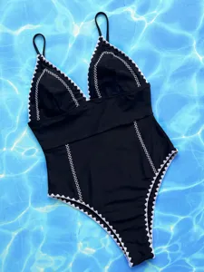 Primo piano di un costume da bagno nero con bordo all'uncinetto bianco e scollo a V.
