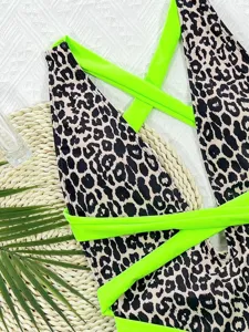 Leopard print one-piece swimsuit detail view, featuring bold neon green cross straps.
