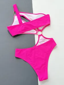 Hot pink asymmetrical cutout one-piece swimsuit detail shot, stylish metal ring accent.
