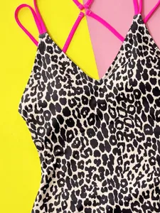 Leopard print one-piece swimsuit detail, featuring vibrant pink cross straps and V-neck.