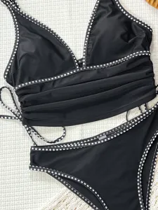 Détail du superbe bikini deux pièces noir avec bordure à pois blancs et design plissé.
