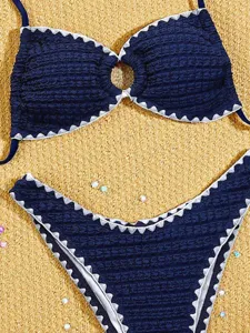 Bikini due pezzi blu navy con bordi smerlati bianchi e dettaglio con anello centrale elegante.