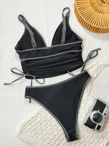 Vue détaillée du bikini noir deux pièces avec bordure à pois blancs et liens latéraux.
