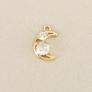 Close-up of gold crescent moon charm with sparkling cubic zirconia, delicate DIY jewelry piece.